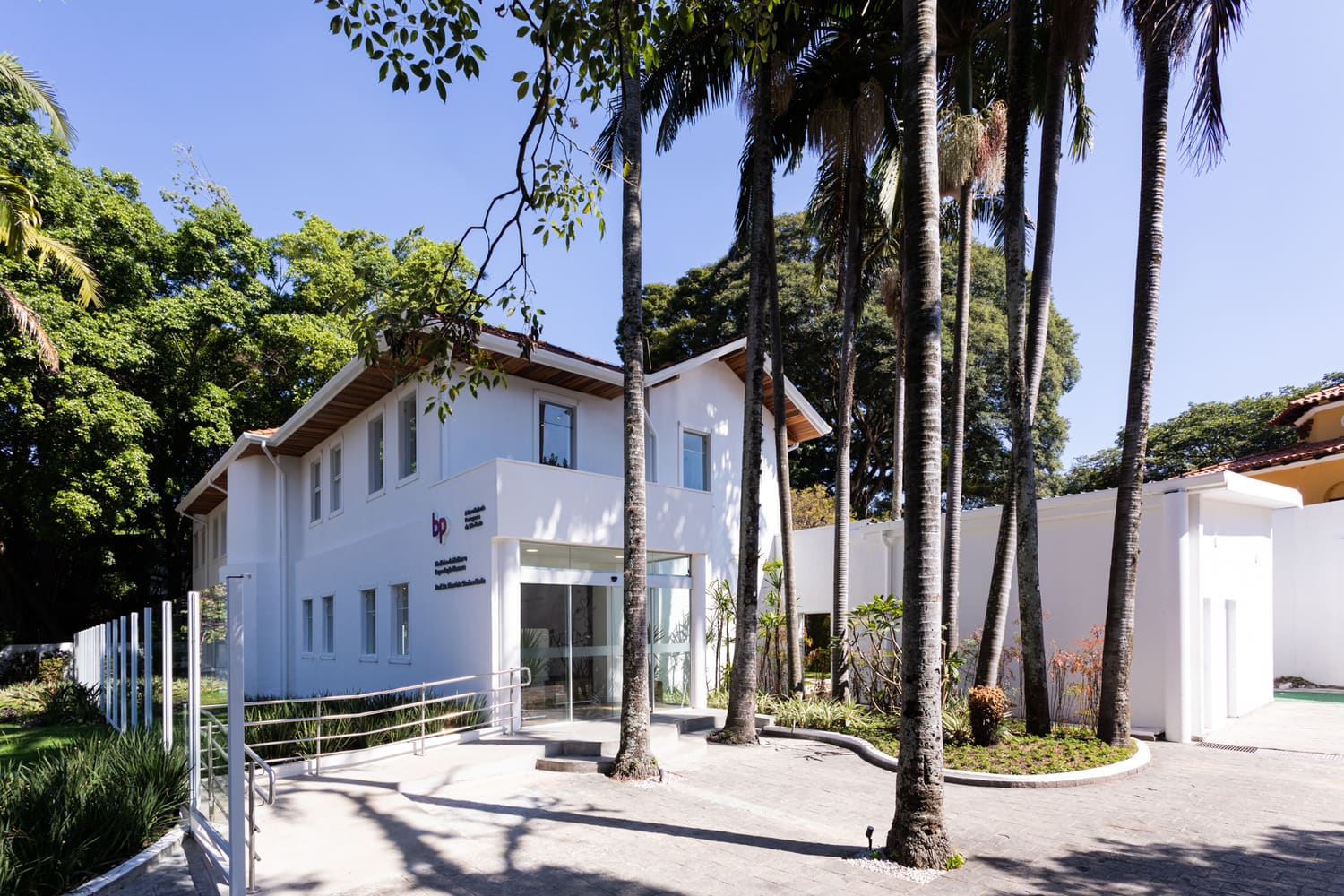 Fachada do consultório da Dra. Marina Andres em São Paulo, edifício branco moderno cercado por palmeiras